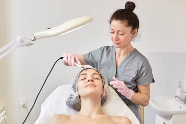 Ultrasonik yüz cilt güzellik salonda profesyonel güzellik uzmanı tarafından tedavi temizlik elde genç çekici kadın. Dermatoloji ferahlatıcı yordam bulunur. Cilt Bakımı ve gençleşme kavramı.