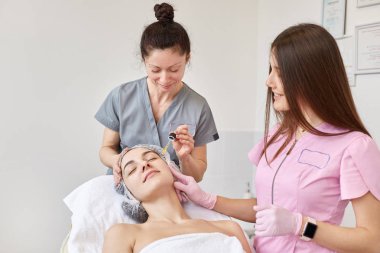 Kozmetik uzmanı serum özü uyguluyor. Temel vitaminler müşterinin cildini geliştirmek için suya su katıyor. Güzellik uzmanı hasta için güzellik tedavisi yapıyor. Sağlık, cilt bakımı, estetik tıp konsepti.