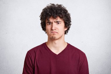 Kasvetli sakallı adam frowns yüz exames, sonuçlarından memnun, neden o kaybeder açıklama talepleri. Beyaz arka plan üzerinde izole siyah kıvırcık saçlı yakışıklı genç adam. İnsanlar ve duygular