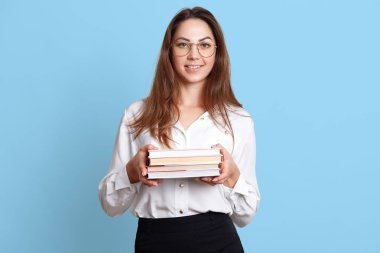 Karizmatik neşeli kız her iki elinde de kitap demet tutar, beyaz bluz ve siyah etek, şık gözlük resmi giyer. Sevimli çekici Bayan eğitim ve uygulama için yüksek ruhları olduğunu.