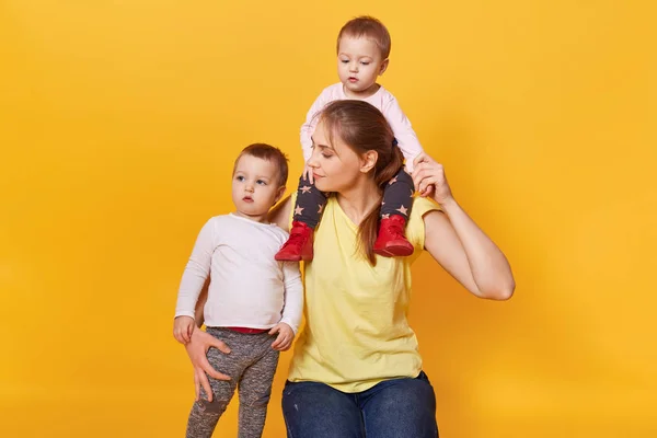 Une mère heureuse tient un enfant sur son cou et un autre câlin serré , — Photo