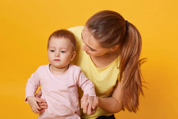 A beautiful young woman embraces her sweet serious child, sit on — Stock Photo, Image