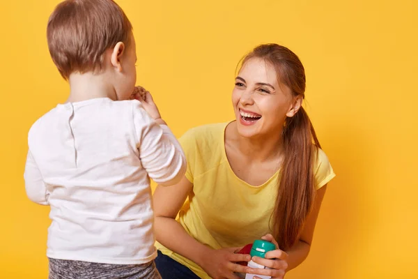 Laughing joyful woman plays with her little cute daughter, spends free time together on the weekends. A young woman is happy to bring up and care her obedient small tiny child. Family concept. — Stock Photo, Image