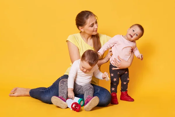 A portrait of active caring mother being busy with her noisy swe — Stock Photo, Image
