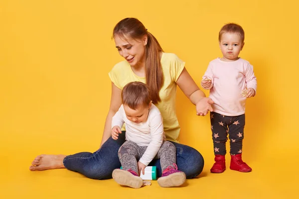 Cansada alegre mujer juega con su activo divertido niños siendo en mate — Foto de Stock