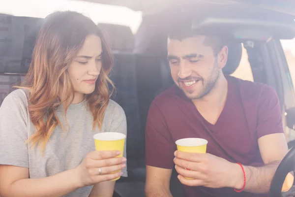 Atraente fêmea e casal masculino sem barba têm coffee break em auto, chegar ao destino wih alta velocidade. Família feliz passar o tempo juntos, viajar no fim de semana, desfrutando de uma vocação legal. Conceito de viagem . — Fotografia de Stock