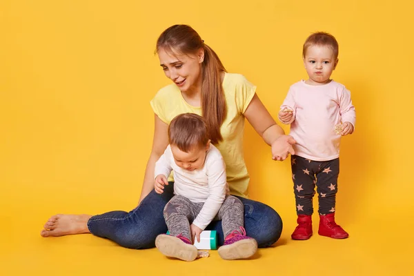 Tired merry woman plays with her active funny kids being on mate Royalty Free Stock Images