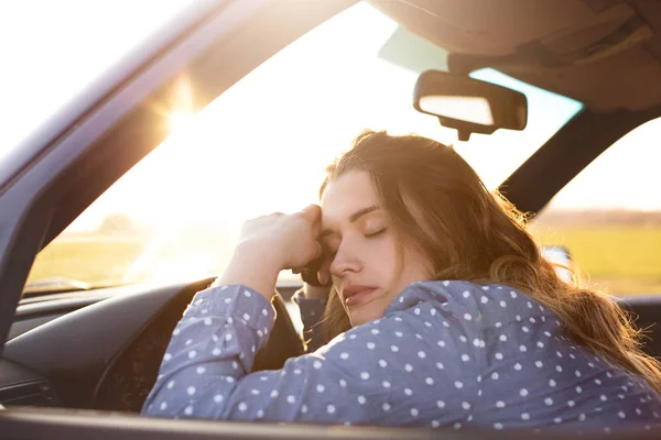 Menina estressada ou cansada no carro deitado com os olhos fechados no volante, pára auto na lateral da estrada, passa longas horas em seu caminho. Mulher bonita adormece enquanto descansa, viaja de veículo . — Fotografia de Stock