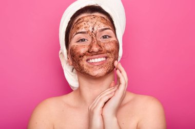 Başında beyaz havlu ile genç kadın Görüntü, çıplak vücut, pembe duvar üzerinde smilling pozlar, yüz yakın katlanmış avuç içi tutar, kozmetik prosedürü yapıyor sahiptir. Slin bakım prosedürleri kavramı.