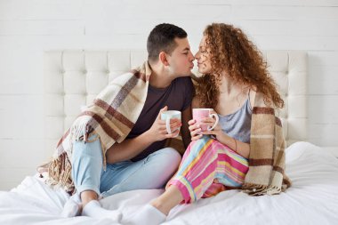Mutlu kadın ve erkek kapalı çekim romantik ilişkiler var, kahve veya çay içmek, yatak odasında ekose ile kaplı. Romantik çift birlikte boş vakit geçirmekten zevk alıyor. İlişki kavramı.