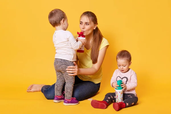 Imagen de la familia feliz, mamá con sus lindos gemelos, mamá juega con sus bebés, hermanas les gusta pasar tiempo con su mamá. Chicas con encanto con botellas, doughter regales madre con leche sabrosa . —  Fotos de Stock