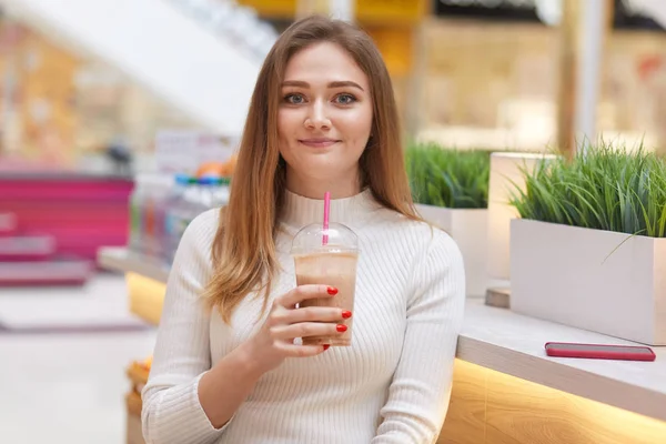 Image de belle jeune femme se trouve dans le café avec cocktail, regarde souriant à la caméra, a de longs cheveux bonde, pull décontracté blanc habillé, être heureux d'avoir du temps libre, femme attrayante. Concept de personnes . — Photo