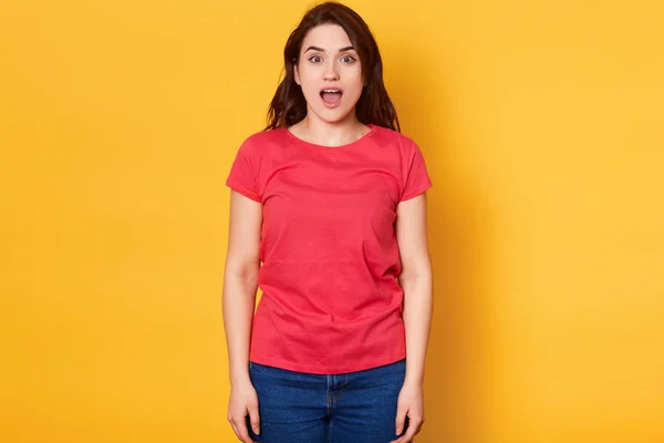 Emocjonalne dziewczyna z zaskoczeniem twarzy expession, wyrazić wielki podziw, ogłoszenia pożądane rzeczy w sklepie, stwarzając z otwartymi ustami, ubrany w casual Red t shirt, izolowane na żółtym tle. — Zdjęcie stockowe