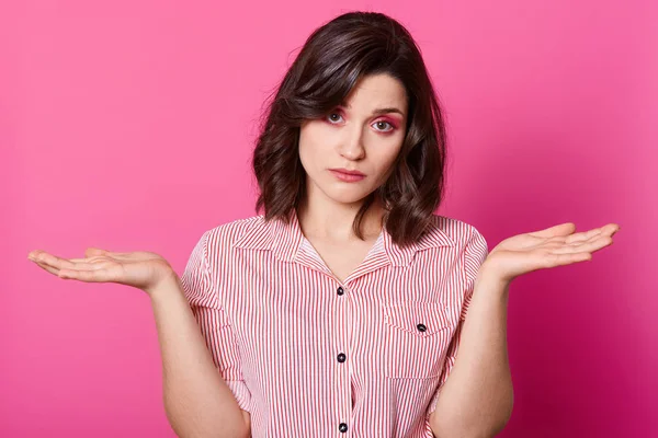 Foto de estudio de mujer atractiva encogiéndose de hombros impotente con las manos, con elegante camisa desnuda, mirando a la cámara con expresión facial triste, tiene problemas, posando contra el fondo del estudio rosa . — Foto de Stock