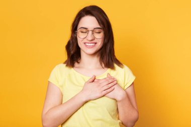 Sevimli kadın Görüntü göğüs üzerinde elleri bir arada tutar, şükran ifade, gözleri kapalı tutar, müteşekkir jest yapar, hoş bir şey için Tanrı'ya şükür. Vücut dili, insan duyguları kavramı.