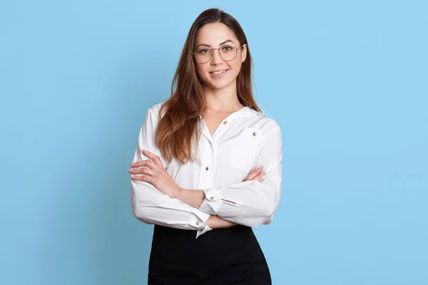 Retrato de pé mulher de negócios alegre em óculos na moda, com braços dobrados, olhando diretamente para a câmera, vestindo blusa branca e saia preta, parece encantado. Conceito de escritório . — Fotografia de Stock