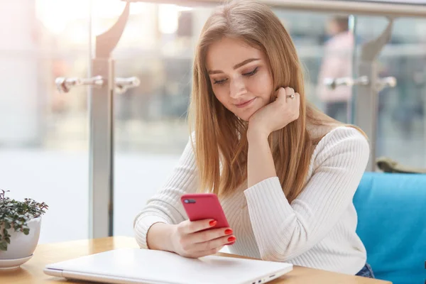 Close up portrait of charming female using mobile phone during break between lectures in coffee shop, young student holding her cell telephone while chatting with friends, using wireless Internet. — Stock Photo, Image