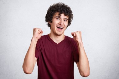 Neşeli çekici Avrupalı erkek heyecanlı ve zafer elde etmek için mutlu olmak Stüdyo çekim, pozitiflik ifade eder, yumruklar sıkıyor, hooray çığlık, gurur hissediyor, şampiyon ve başarılı bir kişi olmak.