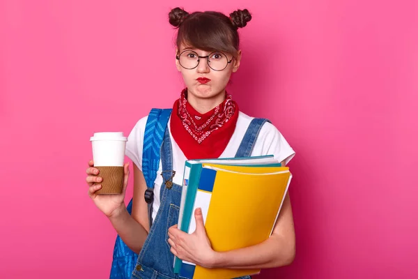 Εικόνα του νεαρού όμορφο μαθητή κρατώντας πρόχειρο και φλιτζάνι καφέ ενώ σκέφτεται την έκθεσή της, αισθάνεται απογοήτευση, απεχθάνεται το θέμα για την έκθεσή της, είναι σε κακή διάθεση, φορώντας μοντέρνα ρούχα. — Φωτογραφία Αρχείου