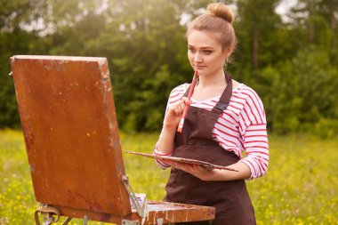 Eskiz defteri kullanarak resim boyama genç kadın sanatçı yatay çekim, kız güzel doğa zevk ve fırça ve renk paleti ile güzel manzara esinlenerek çalışıyor. Sanat Kavramı.