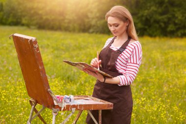 Doğada şöne resim ile güzel kız portresi yakın, genç çekici kadın yaratıcılık dahil ve yaz günü güzel manzara zevk, o seviyor yapmak için mutlu olmak.