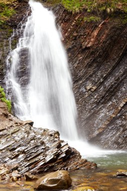 Ormanda azgın şelale etkileyici çekim, kayalıkları boyunca akan su beyaz meşgul akışı, dağ nehirde su seviyesini artırarak, onun canlılık doğa tasvir. Şelale peyzaj konsepti.