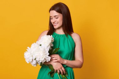 Sarı stüdyo arka planda zarif yeşil Sundress Tarih çekici şık kadın portre yakın, şakayık çiçek buket tutarak, hoş yüz ifadesi, Fells mutlu. Aşk konsepti.