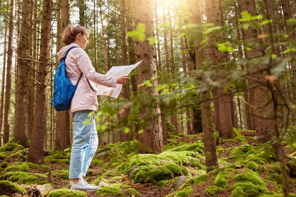 Colpo all'aperto di giovane zaino in spalla slanciato che si ispira ai viaggi, si gode il riposo attivo, tiene la mappa, segue la strada del viaggio, è bravo ad orientarsi, indossa abiti casual. Concetto di attività ricreative . — Foto Stock