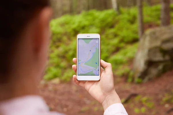 Femme debout au milieu de nulle part, en utilisant l'application de navigation sur smartphone, en suivant l'itinéraire à l'aide de la carte, en regardant l'écran de l'appareil, en utilisant la navigation smartphone tout en vous perdant dans la forêt . — Photo