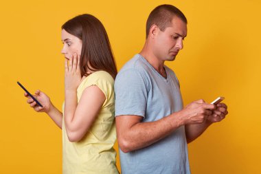 Şok duygusal kadın geri adam geri ayakta, el ile ona yanak dokunmadan, cep telefonu tutarak, onun ekrana bakarak, meşgul adam cihazında haber odaklı, çeşitli mesajlar yazarak.