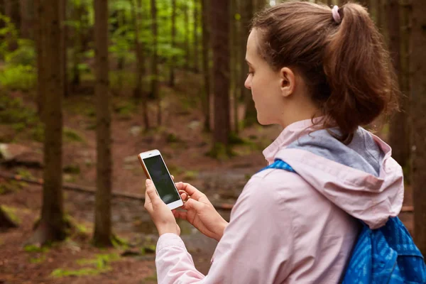 Outdoor-Aufnahme von Backpacker Frau verloren gehen und versuchen, ihren Weg zu finden, mit Online-Karten in Handy im Wald, weibliche Spaziergänge im Wald. Reisen, Rucksackreisen und Abenteuer erleben. — Stockfoto