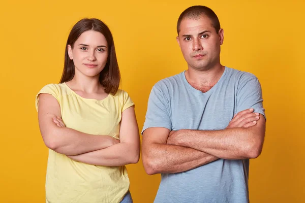 Studio portrait of young beautiful couple marrieds with unhappy faces and negative emotions stare directly at camera with hands folded, have unpleasant news, being offended with one another. — ストック写真