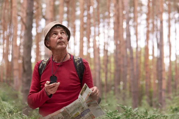 Primo piano colpo di uomo anziano escursioni e guardando il cielo, utilizzando la mappa e bussola per la direzione per il viaggio nella foresta, viaggiare in tutto il mondo, avere avventura nel legno, godersi la sua vacanza attiva . — Foto Stock