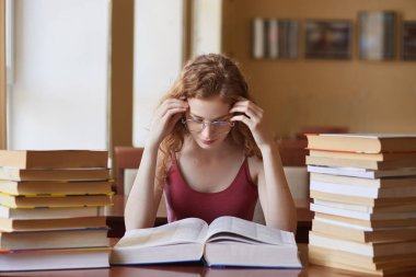 Araştırmaüzerinde çalışan konsantre düşünceli kadın kapalı çekim, özenle kitap açıldı, tapınakyakınında ellerini tutarak, önemli proje için hazırlanıyor, kütüphanede zaman harcama.