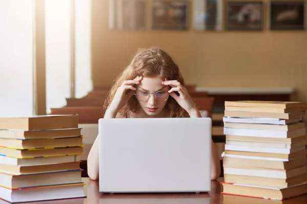 Portrait of stressed busy hard working student coping with all deadlines, being short of time, worried about her home assignments, touching her head with hands, being exhausted by doing tasks. — Stock Photo, Image