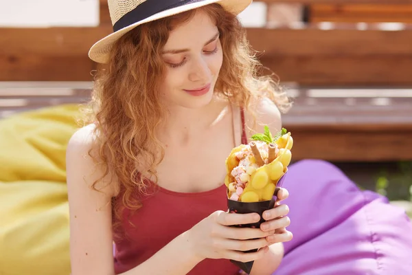 Horisontell skott av söt ung vacker kvinna i hatt och t-shirt, att vara i City Park med glass, att ha vila efter att ha studerat och ha kul med vänner, tillbringar tid i öppen luft. Människor Concept — Stockfoto