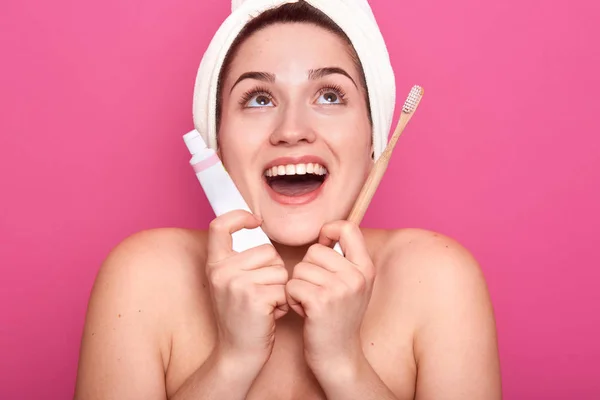 Jonge vrouw met witte handdoek op het hoofd en d nacked schouders, klaar voor het poetsen van tanden, opkijken met open mond en gelukkige gezichtsuitdrukking. Gezond levensstijl en moting procedures concept. — Stockfoto
