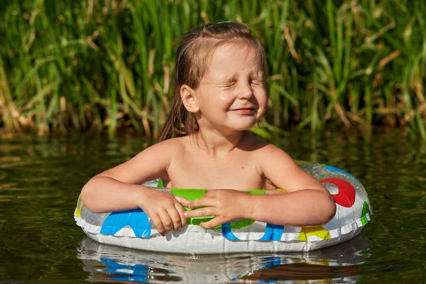 공정한 머리 아름다운 작은 소녀의 초상화는 강에서 수영, 수영 반지의 도움으로 수영을 배우고, 제대로 눈을 감고, 주말 동안 재미있게, 여름을 좋아합니다. 나머지 개념. — 스톡 사진