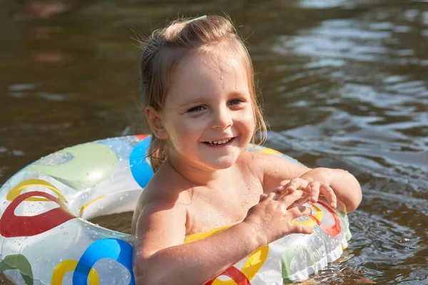 옆으로 찾고, 진심으로 미소, 즐거운 표정, 지역 호수에서 휴가를 보내고, 수영 원으로 수영을 배우는 사랑스러운 재미있는 아이의 초상화를 닫습니다. 어린이 개념. — 스톡 사진
