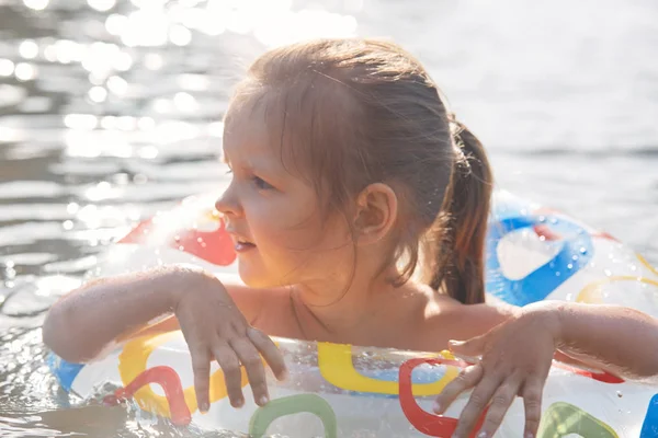 공정한 머리 재미 어린 소녀의 야외 촬영은 호수에서 자유 시간을 보내고, 수영 원으로 수영하는 법을 배우고, 옆으로 보고, 고무 원을 잡고, 물 활동을 즐기고 있습니다. 나머지 개념. — 스톡 사진
