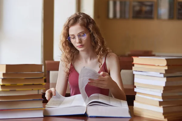 Imagen de una joven trabajadora entregando páginas de un libro enorme, buscando la información adecuada para el proyecto de estudio, haciendo una tarea en casa cuidadosamente. Concepto de estudiante y plazo . —  Fotos de Stock