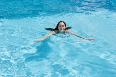 Neşeli sevimli genç bayan açık hava görüntüsü aktif pasttime zevk, boş zaman etkinlikleri düşkün, yüzme havuzu nda açık havada yüzme, doğrudan kameraya bakarak. İnsanlar ve tatil konsepti.