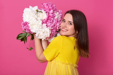 Neşeli mutlu sevimli model portresi stüdyoda pembe arka plan üzerinde izole ayakta, kokulu ve yüz beyaz ve şakayık yakın koyarak, önemli bir olay gidiyor. İnsanlar ve duygular kavramı.