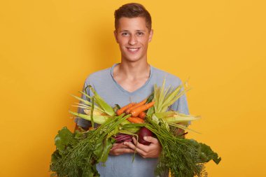 Mağaza veya pazarda bakkal gıda demet taşıyan yakışıklı genç adam yatay çekim. Sarı stüdyo arka planda izole. Reklam veya promosyon için Space Kopyala. Ham gıda ve sağlıklı yeme