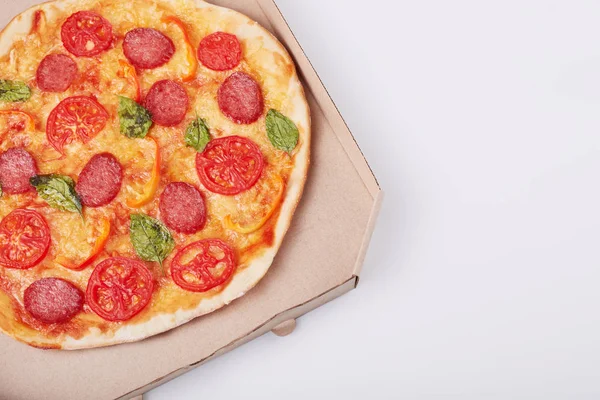 Top view of hot tasty pizza in box with ham sliced and served on white table, close up view. Fast food, junk food and nhealthy eating concept. Copy space for promotion text or your advertisment. — Stock Photo, Image
