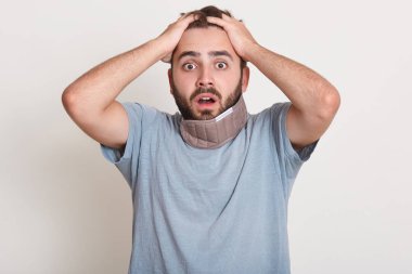 Şoka girmiş genç Avrupalı adamın ellerinin başında, gözleri açık, arkadaşından korkunç şeyler duyduğu, şaşkınlıklarını ifade ettiği, beyaz stüdyo duvarının üzerinde izole edilmiş bir portre. Omg kavramı