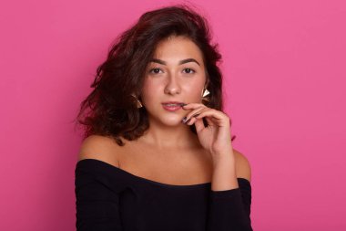 Düşünceli kadın dudakların yanında ön parmak tutar, düşünceler derin olmak, elbiseler siyah gömlek reklam için boş kopya alanı ile pembe arka plan üzerinde izole, emin ifade ile bayan.