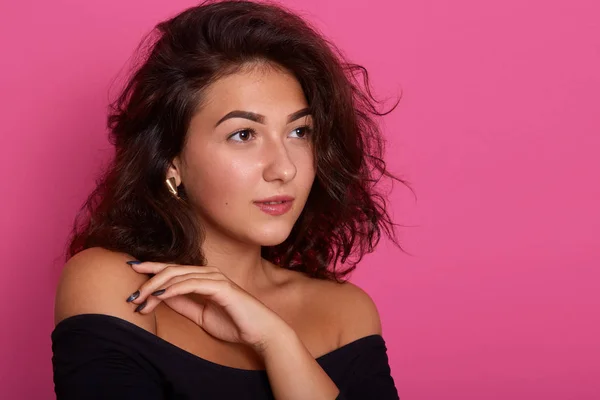 Cabeza de mujer hermosa con cabello ondulado oscuro mirando a un lado sosteniendo la mano cerca de la barbilla. Atractiva hembra con expresión facial segura, mirando a un lado. Copiar espacio para publicidad o promociónen texto . —  Fotos de Stock