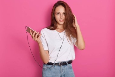 Cep telefonundan müzik dinleyen, sarı pastel stüdyo arka planda izole poz veren, en sevdiği şarkılarla evde dinlenen, güzel Beyaz tenli kadının portresini kapatın. Yaşam tarzı kavramı.