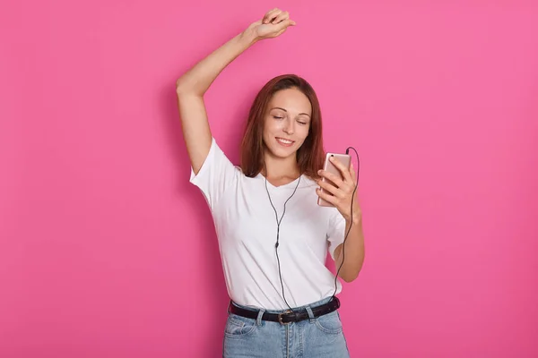 Auriculares mujer de música bailando escuchando música en un reproductor de mp3 o teléfono inteligente. Fresco enérgico feliz multirracial asiático chino / caucásico morena bailarina sobre rosa fondo . — Foto de Stock